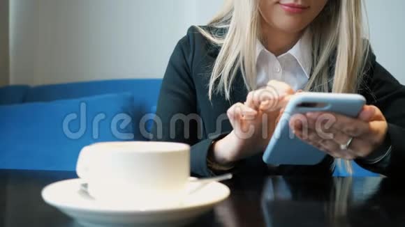 一个穿着西装拿着电话坐在咖啡馆的桌子旁的商务女性视频的预览图