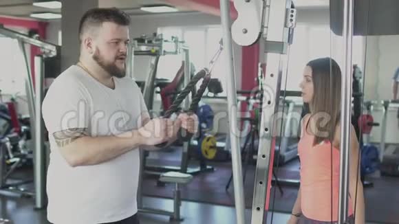 有个人教练的肥胖男人在健身房做体育锻炼超重的男性和女性教练消耗卡路里整体视频的预览图