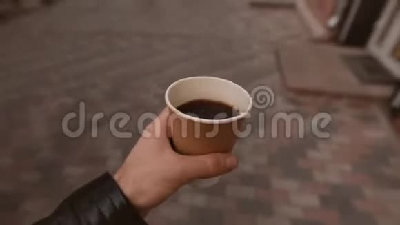 波夫男人拿着咖啡杯在城市大街上散步视频的预览图