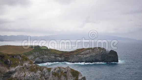 阴云密布的岩石海岸上的海浪俯瞰着这座山视频的预览图