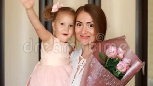 妈妈和宝宝拥抱亲吻妈妈日子或生日妈妈和女儿带着一束鲜花玫瑰视频的预览图