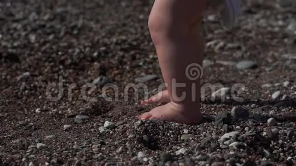 沙滩上一个小男孩的腿带着贝壳动作缓慢视频的预览图