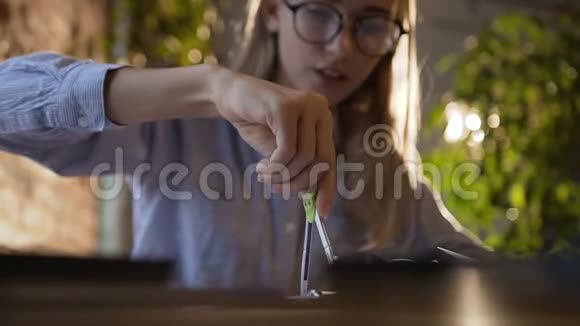 一个戴着眼镜的漂亮学生女孩坐在桌子旁用一张纸上的指南针她画了一张视频的预览图