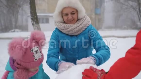 妈妈和两个女儿在冬天堆雪人视频的预览图