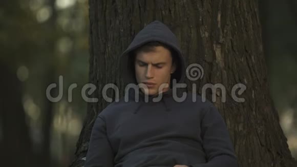 公园里坐在树下的沮丧男人失业问题困难视频的预览图