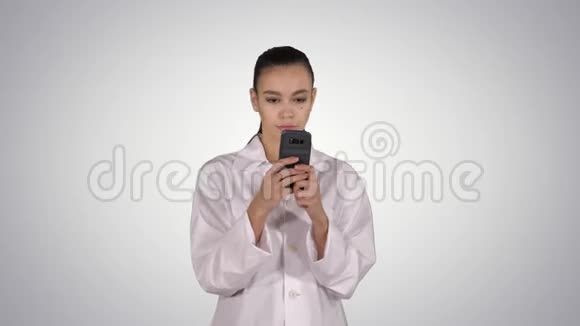 性格开朗可爱的年轻女医生一边打电话一边走在渐变的背景下视频的预览图