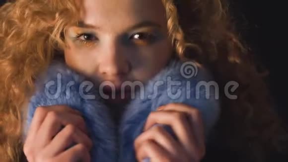 头发卷曲的年轻女人把脸藏在毛皮领子里视频的预览图