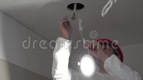 熟练的电工将现代LED灯安装到天花板上视频的预览图