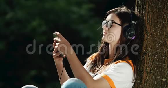 戴耳机的女人在公园听音乐视频的预览图