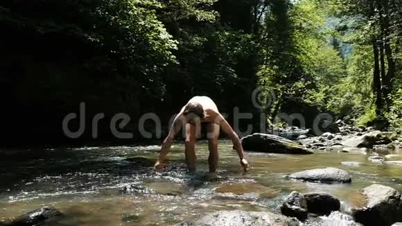 夏天人在一条山河里飞溅那家伙站在水里像个孩子一样快乐动作缓慢视频的预览图
