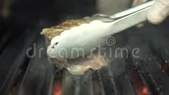 厨师双手戴白色防护手套在烧烤上翻出新鲜美味的牛排行动烹饪近景视频的预览图