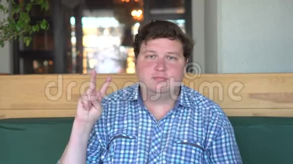 一个身材高大英俊的胖子在咖啡馆或餐馆里展示胜利标志视频的预览图
