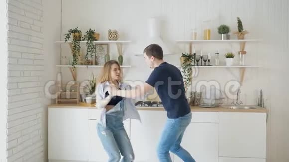 年轻快乐的一对夫妇在家里的厨房里跳舞很开心视频的预览图