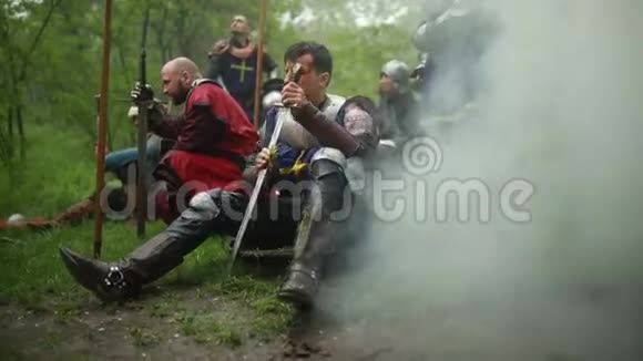 一位中世纪的骑士坐在盔甲上清洗他的剑视频的预览图