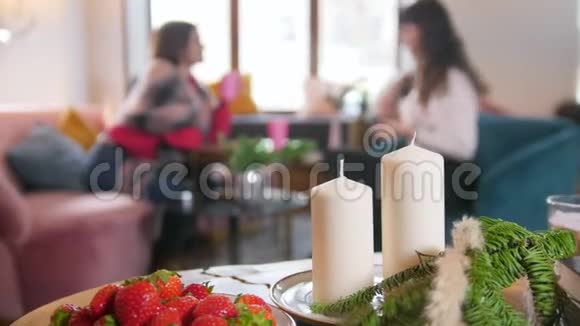 两个年轻的女人坐在咖啡馆里聊天前景上的蜡烛视频的预览图