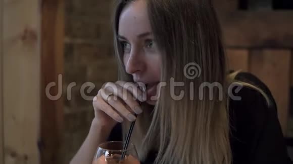 令人高兴的金发女人在酒杯里喝鸡尾酒用黑色吸管喝穿着时髦视频的预览图