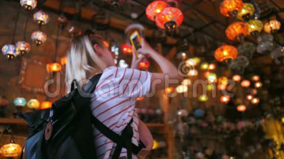 旅游妇女在纪念品商店用传统灯具用智能手机拍照视频的预览图