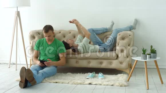 一对夫妇在家舒适的沙发上使用数字设备视频的预览图