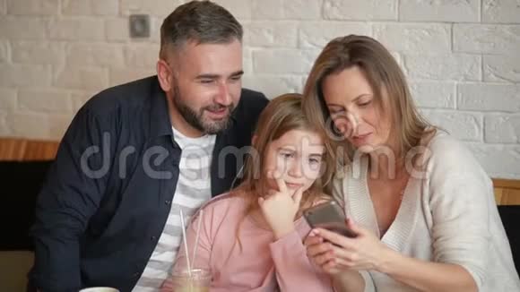 幸福家庭在SmarthphoneIndoors上做自拍的肖像他们在咖啡厅度过这美好的一天视频的预览图