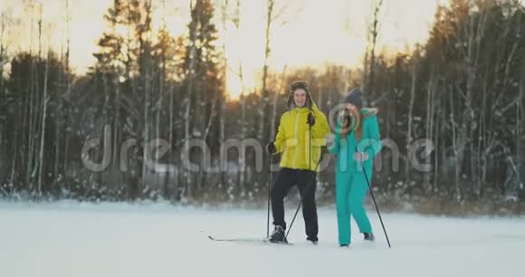 年轻夫妇载着滑雪板在美丽的冬林中聊天复制空间的侧视图视频的预览图
