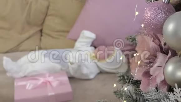 一个新生婴儿躺在圣诞树附近的沙发上视频的预览图