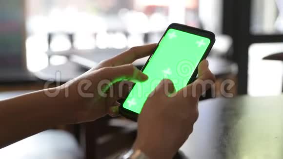 在餐厅使用绿色屏幕手机的女性手部特写视频的预览图