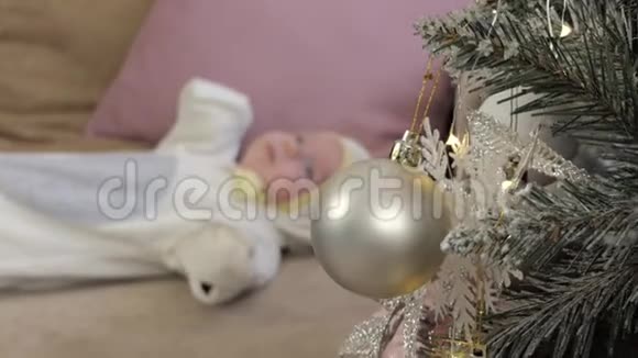 一个新生婴儿躺在圣诞树附近的沙发上视频的预览图