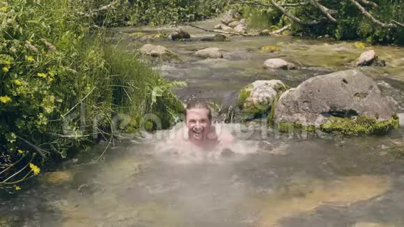 夏天微笑的人在冰冷的河水里洗澡慢动作视频的预览图