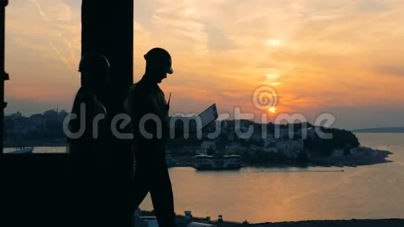 两个建筑工人在日落背景侧视视频的预览图