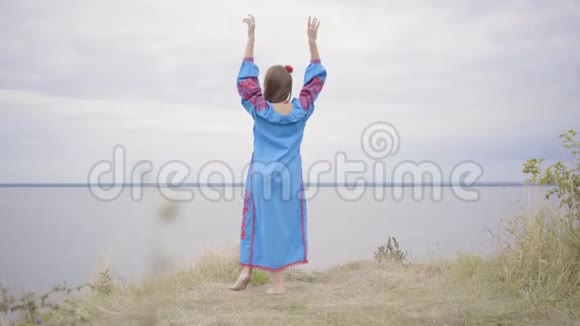后景为无忧无虑的白种人年轻女子穿着夏日的长裙站在田野的背景下视频的预览图