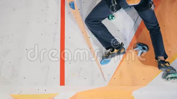人踩着攀岩墙上的岩石靠近视频的预览图