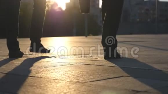 两个商人的脚在城市街道上行走背景是太阳耀斑商人们一起上下班视频的预览图
