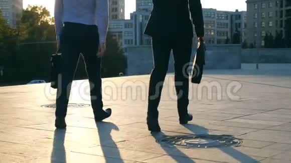 两个商人带着公文包走在城市街道上背景是太阳耀斑商务人员上下班视频的预览图