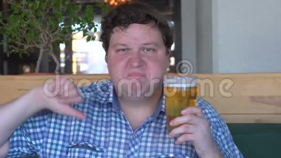 不满的年轻人拿着一杯啤酒伸出大拇指视频的预览图