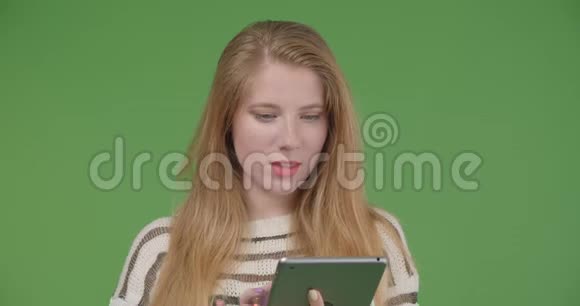 用平板电脑拍摄年轻漂亮的白种人女性的特写镜头并用背景镜头显示蓝色屏幕视频的预览图