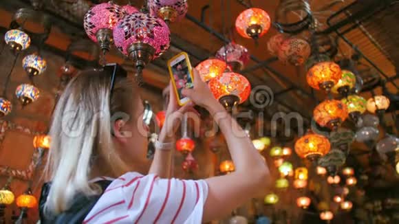 旅游妇女在纪念品商店用传统灯具用智能手机拍照视频的预览图