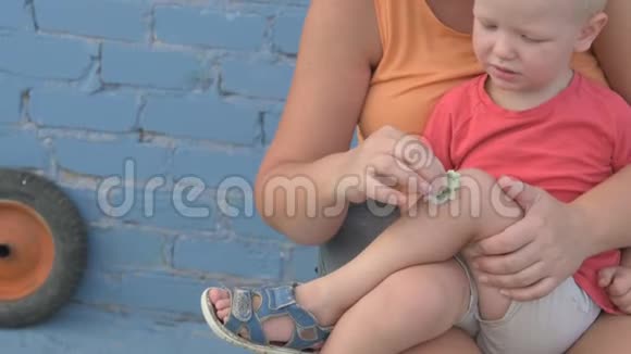 年轻的母亲用酒精婴儿的膝盖上擦破了保健保护温柔视频的预览图
