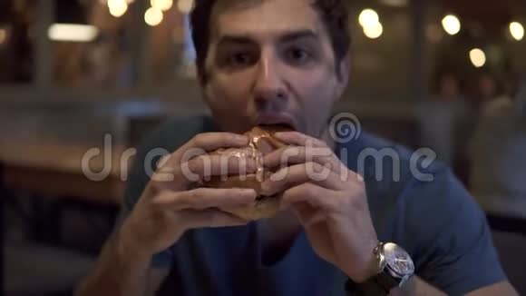 布鲁内特先生在一家餐馆或快餐店吃汉堡包他饿了吃了一大口持有视频的预览图