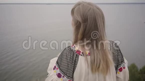 后景在无忧无虑的白种人女人穿着夏日的长时装站在田野的背景上视频的预览图