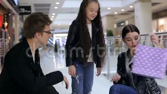 年轻时尚的女孩父母在购物袋里看购物视频的预览图