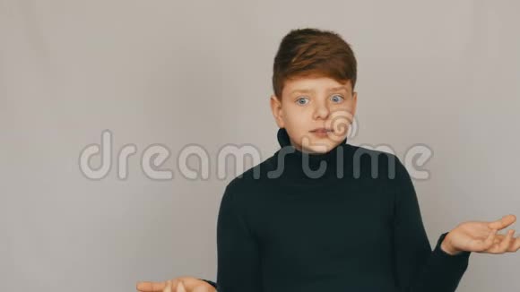 一个滑稽的红头发和蓝眼睛的少年男孩的肖像用手势和面部表情表示谴责视频的预览图
