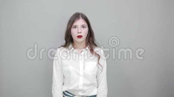 困惑的年轻女子穿着白色衬衫张开双手看着镜头视频的预览图