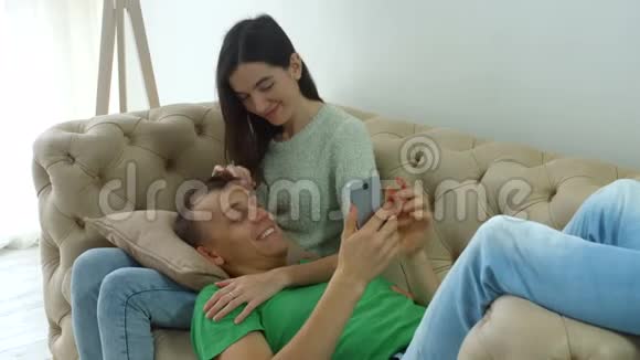 沙发上的情侣享受智能手机的媒体内容视频的预览图