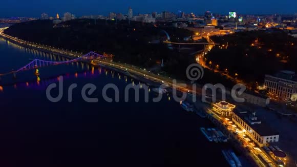 夜间基辅超脱丹妮珀河岸上五颜六色的人行桥空中镜头视频的预览图