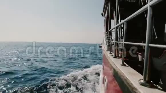 相机在游轮的左侧在开阔的海洋中快速航行在晴朗的晴天切割蓝色的泡沫波视频的预览图