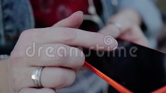 女孩在坐在城市公园的长凳上的智能手机触摸屏上滑动手指手的特写视频的预览图