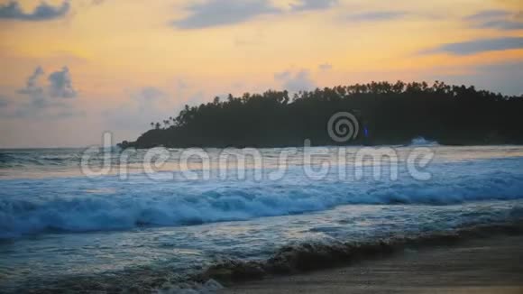 美丽的背景拍摄田园金色日落在惊人的海洋度假海滩和棕榈岛与泡沫白色的波浪视频的预览图