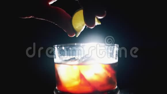 将石灰或柠檬挤在新鲜水果鸡尾酒上威士忌和可乐在深色背景和室内灯光下加冰块视频的预览图