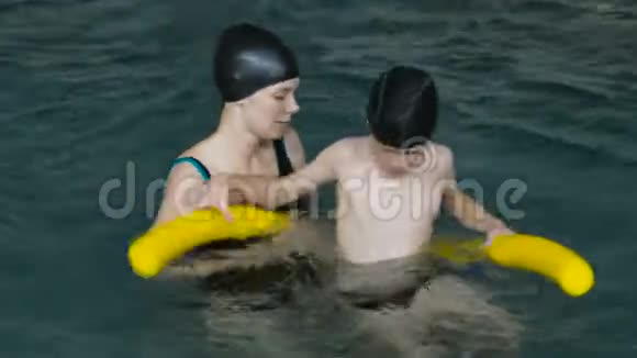 妈妈教七岁的儿子在游泳池游泳视频的预览图