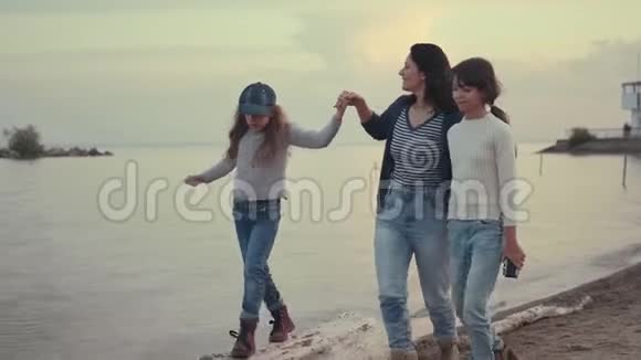 一家人一起呆在户外日落时分年轻的母亲和她的孩子们在海滨散步视频的预览图